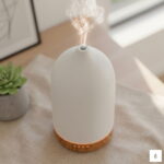 Biały ceramiczny dyfuzor PureSense emitujący delikatną, zimną mgiełkę zapachową na tle jasnego wnętrza